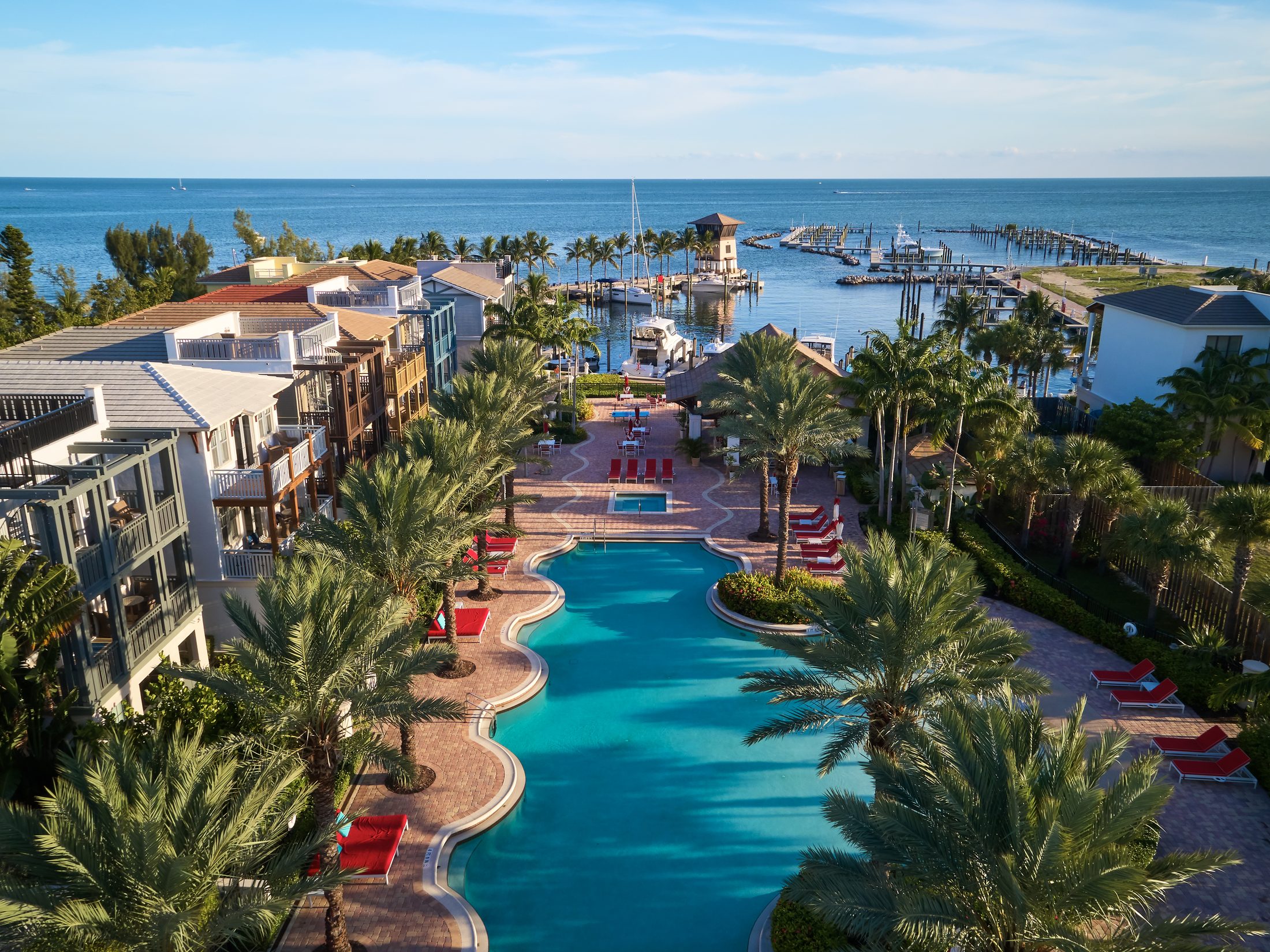 Aerial view of Marlin Bay Yacht Club in Marathon, Florida Keys — resort pool, three-story waterfront homes, and 99-slip deep-water marina on Florida Bay